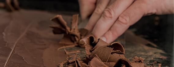 Image d'illustration nos savoir-faire représentant un chocolatier faisant des copeaux de chocolat